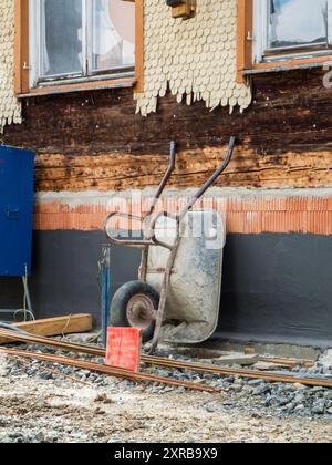 Reconstruction du chantier de construction d'une maison en bois en Bavière avec une brouette placée contre le mur. Banque D'Images