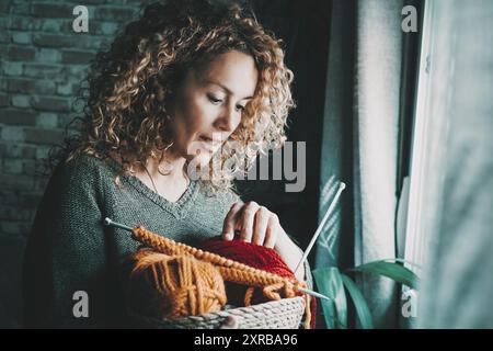 Belle femme bouclée de 47 ans choisit la laine pour commencer un processus fait à la main. Journée tranquille à la maison créant. Concept de personnes Banque D'Images