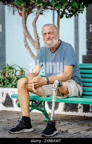 Homme âgé avec une jambe prothétique gauche repose sur un banc de parc. Passez un après-midi de détente. Concept de personnes Banque D'Images