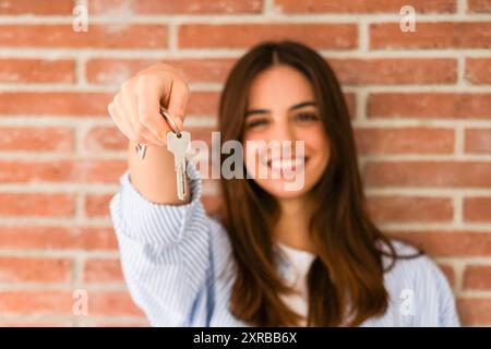 Femme heureuse tenant les clés de la nouvelle maison, regardant la caméra et souriant. Portrait de premier acheteur, propriétaire de maison, locataire d'appartement, locataire d'appartement ou propriétaire. Jour de déménagement et achat concept de propriété propre Banque D'Images