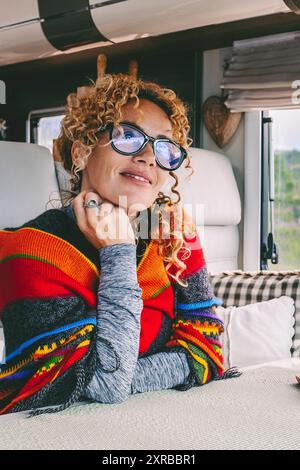 Une femme voyageuse heureuse profiter de vanlife liberté style de vie seul assis à l'intérieur du camping-car moderne. Vue sur le parc à l'extérieur de la fenêtre. Vivre hors réseau sur le voyage. Location de véhicule de camping-car concept de vacances. Aventure Banque D'Images