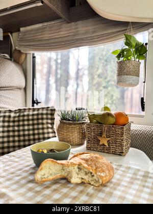 Intérieur du camping-car camping-car avec de la nourriture sur la table et vue de gorest à l'extérieur de la fenêtre. Concept de vanlife et voyage gens de vacances style de vie Banque D'Images