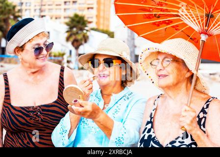 Trois femmes matures portant des chapeaux de plage et souriant debout sur une plage tropicale. Les dames plus âgées s'amusent dans l'activité de loisirs en plein air dans le style de vie d'été de vacances. Mode de vie des amis âgés Banque D'Images