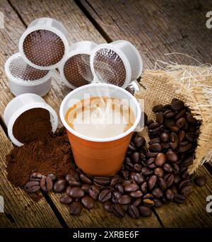 Expresso avec gobelet jetable avec pods sur table en bois Banque D'Images