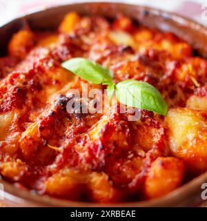 Gnocchi alla Sorrentina, boulettes de pommes de terre italiennes à la sauce tomate, gratinées avec du fromage mozzarella dans un plat en terre cuite. Mise au point sélective. Banque D'Images
