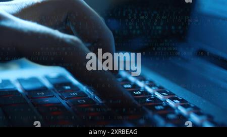 Homme tapant sur le clavier de l'ordinateur avec superposition de code binaire Banque D'Images