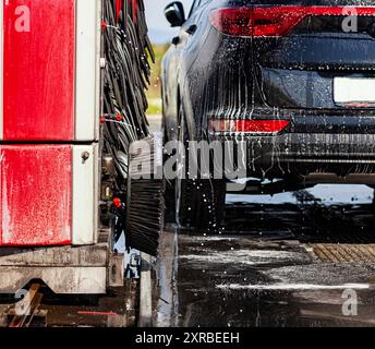 Black car en rotation automatique de lavage de voiture brosse rouge et noir. Détail de la lave de jantes en alliage. Banque D'Images