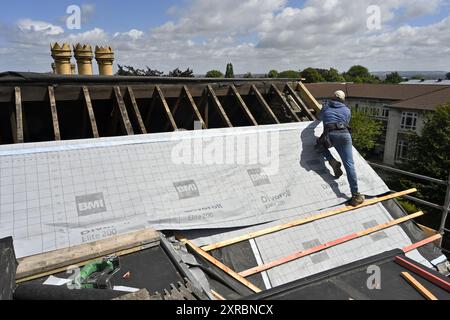 Travaux de toiture, homme sur le toit installant la membrane de toiture, Royaume-Uni Banque D'Images