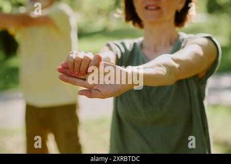 Gros plan moyen des mains manucurées féminines pendant l'exercice d'étirement musculaire du bras Banque D'Images