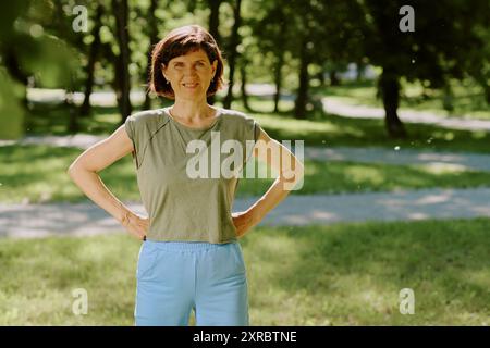 Portrait de femme brune souriante habillée de vêtements de sport en coton regardant directement la caméra tout en ayant une séance d'entraînement en plein air Banque D'Images