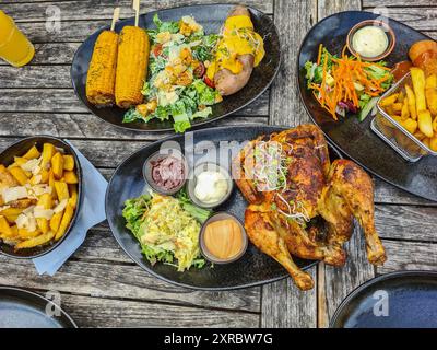 Gril grillé avec frites et maïs, salade et trempettes sur des assiettes à l'extérieur sur une table en bois, Restaurant am Strandübergang à Prerow, Mecklembourg-Poméranie occidentale, Allemagne Banque D'Images