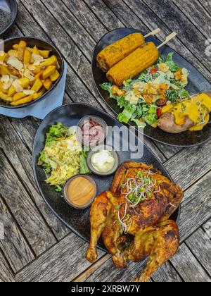 Gril grillé avec frites et maïs, salade et trempettes sur des assiettes à l'extérieur sur une table en bois, Restaurant am Strandübergang à Prerow, Mecklembourg-Poméranie occidentale, Allemagne Banque D'Images