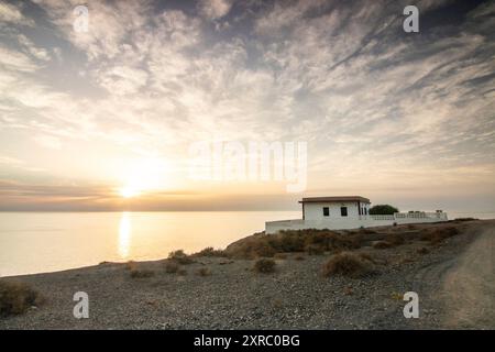 Lever de soleil avec vue sur la mer sur une côte rocheuse aux couleurs chaudes, paysage avec une maison sur la plage de Tarajalejo à Fuerteventura, îles Canaries, Espagne. Banque D'Images