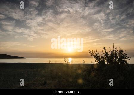 Lever de soleil avec vue sur la mer dans une baie avec plage de sable et pierres, côte rocheuse aux couleurs chaudes, paysage de Tarajalejo à Fuerteventura, îles Canaries, Espagne Banque D'Images