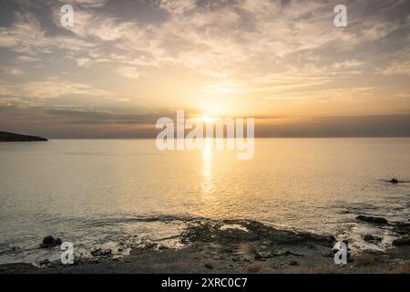 Lever de soleil avec vue sur la mer dans une baie avec plage de sable et pierres, côte rocheuse aux couleurs chaudes, paysage de Tarajalejo à Fuerteventura, îles Canaries, Espagne Banque D'Images