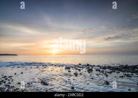 Lever de soleil avec vue sur la mer dans une baie solitaire, côte rocheuse aux couleurs chaudes, paysage avec plage de lave de Tarajalejo sur Fuerteventura, îles Canaries, Espagne Banque D'Images