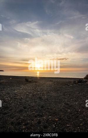 Lever de soleil avec vue sur la mer dans une baie solitaire, côte rocheuse aux couleurs chaudes, paysage avec plage de lave de Tarajalejo sur Fuerteventura, îles Canaries, Espagne Banque D'Images