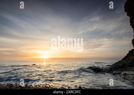 Lever de soleil avec vue sur la mer dans une baie solitaire, côte rocheuse aux couleurs chaudes, paysage avec plage de lave de Tarajalejo sur Fuerteventura, îles Canaries, Espagne Banque D'Images