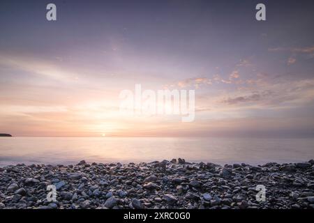 Lever de soleil avec vue sur la mer dans une baie solitaire, côte rocheuse aux couleurs chaudes, paysage avec plage de lave de Tarajalejo sur Fuerteventura, îles Canaries, Espagne Banque D'Images