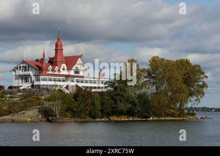 Cette image capture un bâtiment historique en bord de mer avec des toits rouges distinctifs, niché sur une petite île au bord de l'eau. L'architecture présente un b Banque D'Images