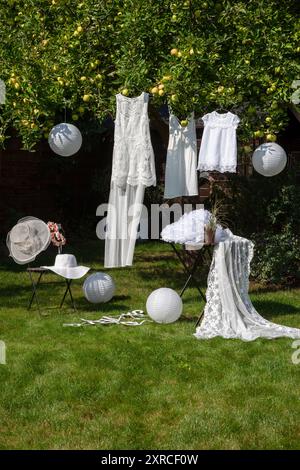 Robes blanches festives pour les femmes et les enfants accrochés à un pommier dans le jardin, en choisissant une robe de mariée, en préparant le mariage Banque D'Images