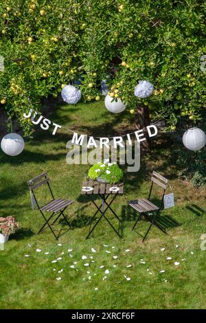 Une guirlande avec l'inscription Just Married est suspendue à un pommier avec des pommes vertes et des lanternes blanches dans le jardin, un signe avec l'inscription M Banque D'Images