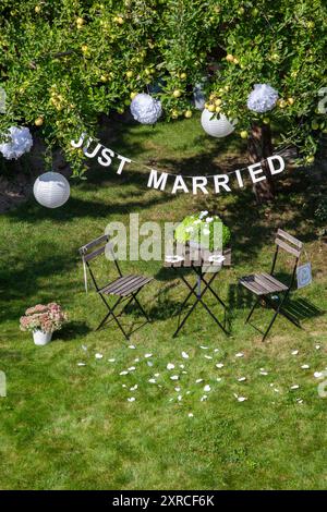 Une guirlande avec l'inscription Just Married est suspendue à un pommier avec des pommes vertes et des lanternes blanches dans le jardin, un signe avec l'inscription M Banque D'Images