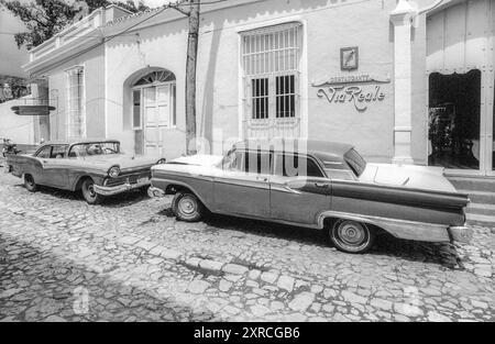 2001 photographie d'archives en noir et blanc de vieilles voitures américaines devant le restaurant via Reale à Trinidad, Cuba. Banque D'Images