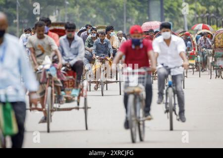 Les tireurs de pousse-pousse transportent des passagers sur la route de l'aéroport, dans la matinée à Dhaka, le lundi 11 juillet. Les pousse-pousse sont normalement interdits d'utilisation des routes, mais sont autorisés pendant le verrouillage actuel. Le Bangladesh traverse une vague de COVID-19, avec un record de 13768 cas le lundi 12 juillet. Le 14 juillet, les restrictions au confinement seront assouplies pendant neuf jours pour les célébrations d'Eid-ul-Azha. Les tireurs de pousse-pousse comptent parmi les travailleurs les moins bien payés au Bangladesh et ont ressenti les restrictions très durement. Au cours des efforts précédents sur le verrouillage, les tireurs de pousse-pousse où Banque D'Images