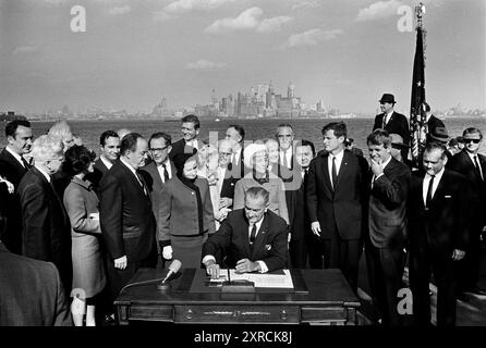 Le président américain Lyndon B. Johnson signant l'Immigration and Nationality Act de 1965 en tant que vice-président américain Hubert Humphrey, Lady Bird Johnson, Muriel Humphrey, sénateur Edward Kennedy sénateur Robert Kennedy, et d'autres regardent sur Liberty Island, New York City, New York, États-Unis, Yoichi Okamoto, 3 octobre 1965 Banque D'Images