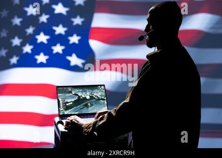 Répartiteur de l'armée américaine utilisant le microphone casque, offrant des informations stratégiques aux commandants combattant sur les lignes de front. Opérateur du centre de commandement fournissant intel pour les troupes, isolé au-dessus du drapeau américain Banque D'Images