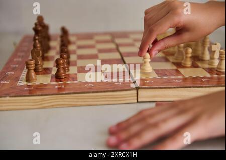Gros plan de deux mains déplaçant des pièces d'échecs sur un échiquier en bois, capturant l'intensité et la stratégie du jeu. Banque D'Images