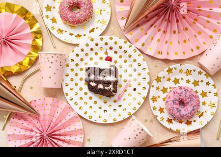 Assiettes en papier avec friandises sucrées et décor pour fête d'anniversaire sur fond de couleur Banque D'Images