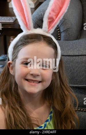 Fille de 6 ans portant des oreilles de lapin sourit joyeusement le dimanche de Pâques. ÉTATS-UNIS Banque D'Images