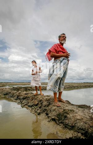 G. M. Abdus Sabur est inquiète. - Si nous n'obtenons pas mieux levées et des barrières contre les inondations, nous va se noyer. Comme il le stand avec sa nièce sur le bord d'une galette de riz, il espère le monde prendre note et aider à arrêter l'eau de monter. Le Bangladesh est sujet à un double coup de l'inondation et la sécheresse causée par la fonte des glaciers de l'Himalaya. Banque D'Images