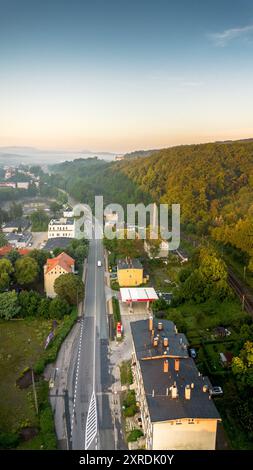Vue aérienne d'une ville tranquille le long d'une route sinueuse entourée de verdure luxuriante au petit matin Banque D'Images