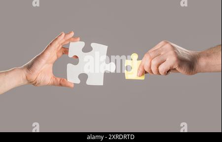 Mains d'hommes assemblant différentes pièces de puzzle de couleur. Concept de travail d'équipe. Les mains humaines tiennent, assemblant des pièces de puzzle. Homme d'affaires mains corporatif Banque D'Images
