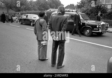 Blair Peach le cortège funéraire fait son chemin à travers Southall sur la route du cimetière. Un chauffeur de bus et le conducteur arrêtent leur bus et rendent hommage au passage du cortège funéraire. (Conducteur de bus asiatique (l) tenant son distributeur de billets et chauffeur de bus avec arc (?) En cheveux longs) Southall, Londres, Angleterre 13 juin 1979. ANNÉES 1970 ROYAUME-UNI HOMER SYKES Banque D'Images