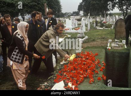 Blair Peach Funeral années 1970 Southall, West London. Au cimetière, des membres de la communauté asiatique laissent des œillets rouges sur sa tombe. Des œillets rouges profonds à tige unique sont jetés sur la tombe, alors que les membres de la communauté Silk attendent leur tour pour dire adieu. Blair Peach était un membre actif de la Ligue anti-nazie et de l'Inner London Teachers Association. Southall, Londres, Angleterre 13 juin 1979. HOMER SYKES Banque D'Images