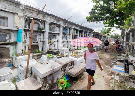 Femme passant des tombes au cimetière de Carreta à Cebu City, Philippines Banque D'Images