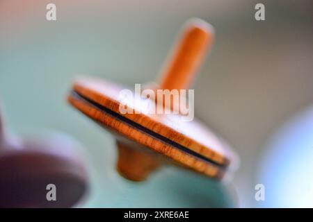 Photo macro d'un teetotum en bois tournant et debout sur une surface en verre, mettant en valeur son savoir-faire complexe et sa surface lisse et réfléchissante. Banque D'Images