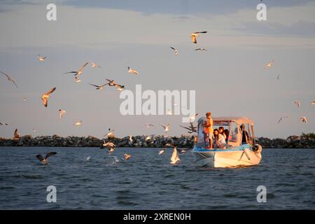 Touristes sur un bateau entouré de mouettes sur la mer Noire près de Sulina, Roumanie Banque D'Images