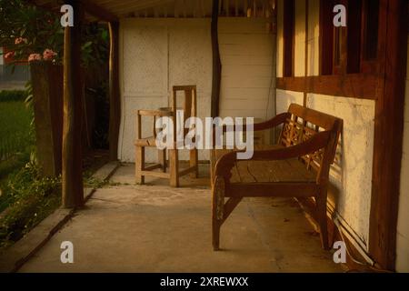 chaises anciennes en bois vintage sur le porche d'une simple maison rustique en bois à la campagne avec réflexion de la lumière du soleil Banque D'Images