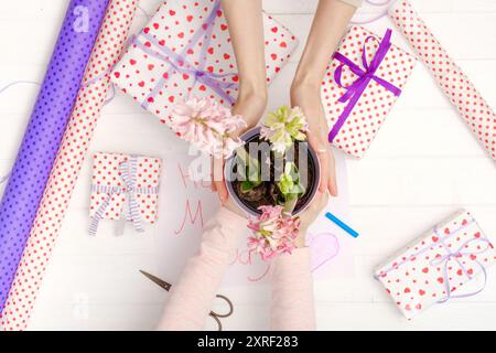 Mains de mère et petite fille avec fleurs et cadeaux. Vue de dessus. Concept de vacances. Banque D'Images