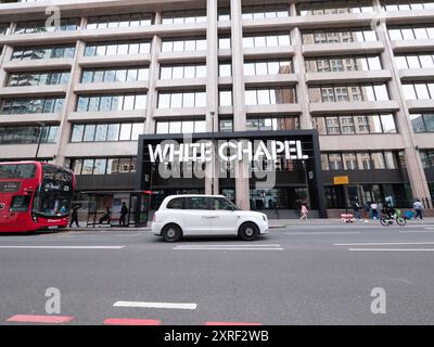 Le White Chapel Building, un parc d'affaires moderne à Whitechapel, Londres, avec un taxi blanc passant au premier plan, Royaume-Uni Banque D'Images