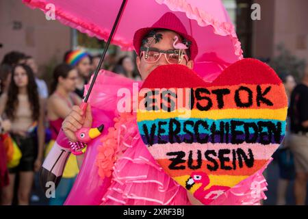 Francfort, Allemagne. 10 août 2024. « C'est OK d'être différent » est écrit sur le cœur auto-fabriqué d'un participant vêtu de rose au Christopher Street Day (CSD) Francfort sous la devise « nous sommes extrêmement amoureux ». Photo : Helmut Fricke/dpa/Alamy Live News Banque D'Images