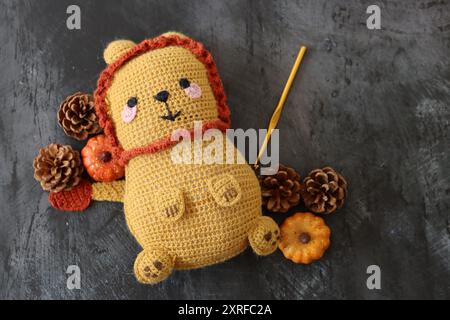 Gros plan du jouet en peluche Lion crocheté. Poupée de tapis à la main mignonne sur fond texturé foncé avec espace de copie. Banque D'Images