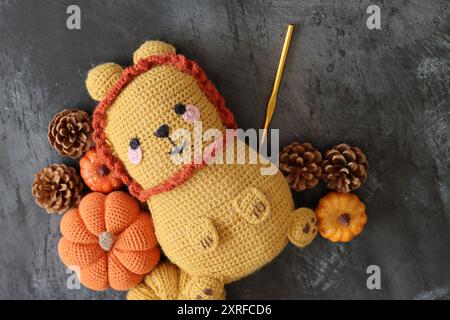 Gros plan du jouet en peluche Lion crocheté. Poupée de tapis à la main mignonne sur fond texturé foncé avec espace de copie. Banque D'Images