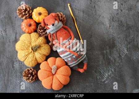 Décoration d'Halloween avec des citrouilles, jouet Fox crocheté et fil de laine orange sur fond gris avec espace pour le texte. Cadeau d'automne fait à la main. Banque D'Images