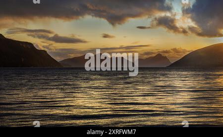 Paysage dans le fjord de Norvège à Skaland sur l'île de Senja au coucher du soleil sur la mer avec des collines à l'arrière Banque D'Images